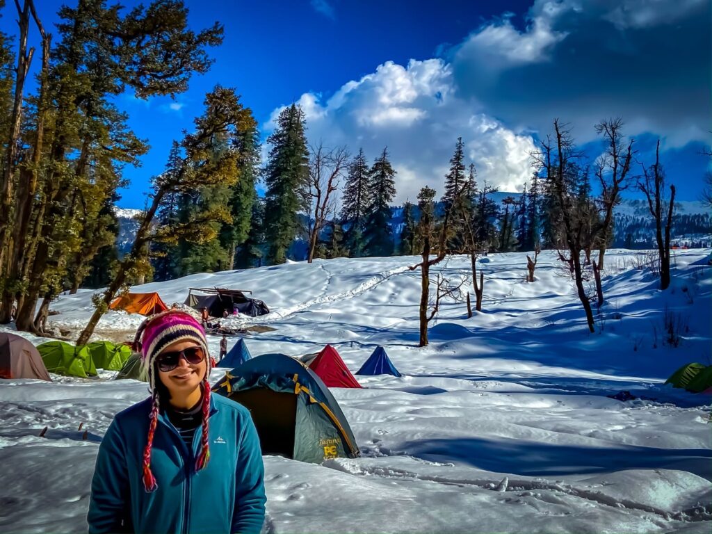 a woman standing in the snow with tents and trees