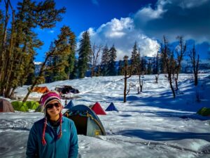 a woman standing in the snow with tents and trees